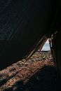 Blue water of sea in sunlight from under dark camping tent placed on shoreline