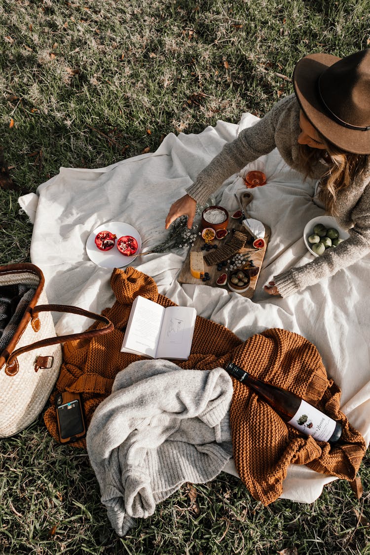 Woman Having Picnic On Grass With Book