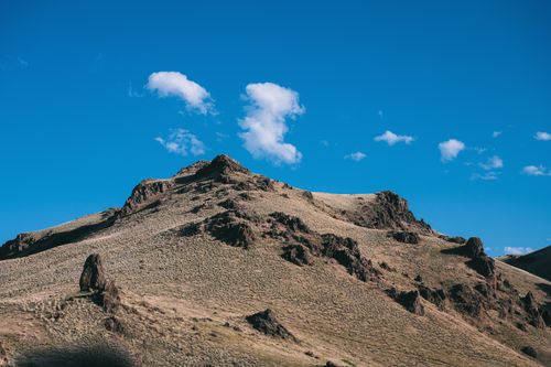 Free Picturesque scenery of hills with dry grass and rocky formations under blue sky Stock Photo