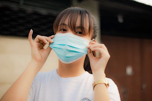 Free Portrait of a young woman wearing a blue face mask outdoors, highlighting pandemic safety. Stock Photo