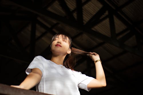 Woman in White Crew Neck T-shirt Holding Her Hair