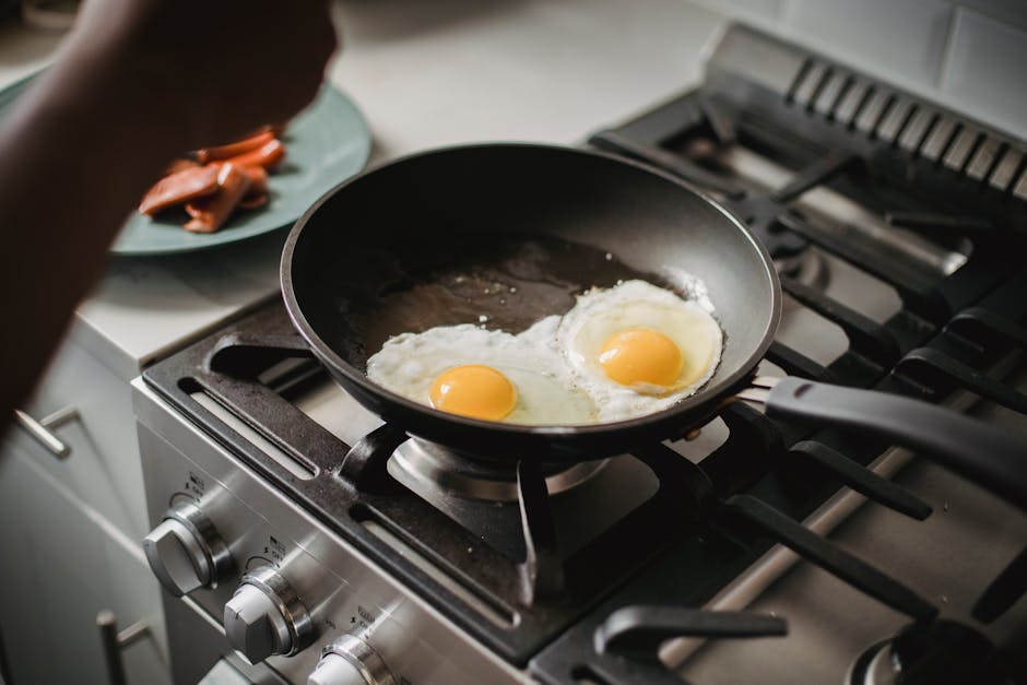 Carbon Steel vs Cast Iron: High-Heat Cooking Showdown Close-up of two fried eggs cooking in a frying pan on a modern stovetop.