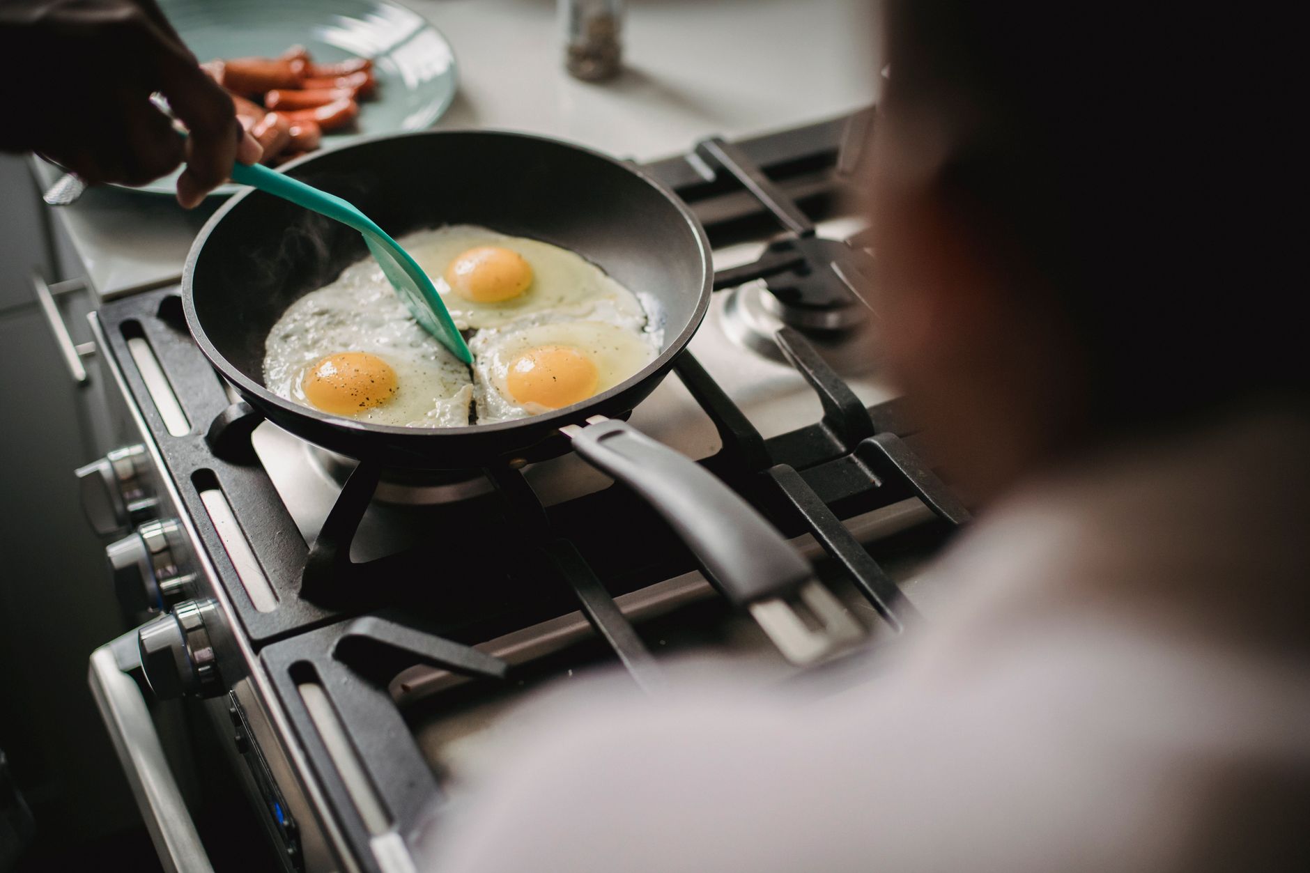 A stainless steel frying pan with a wooden handle on a gas stove