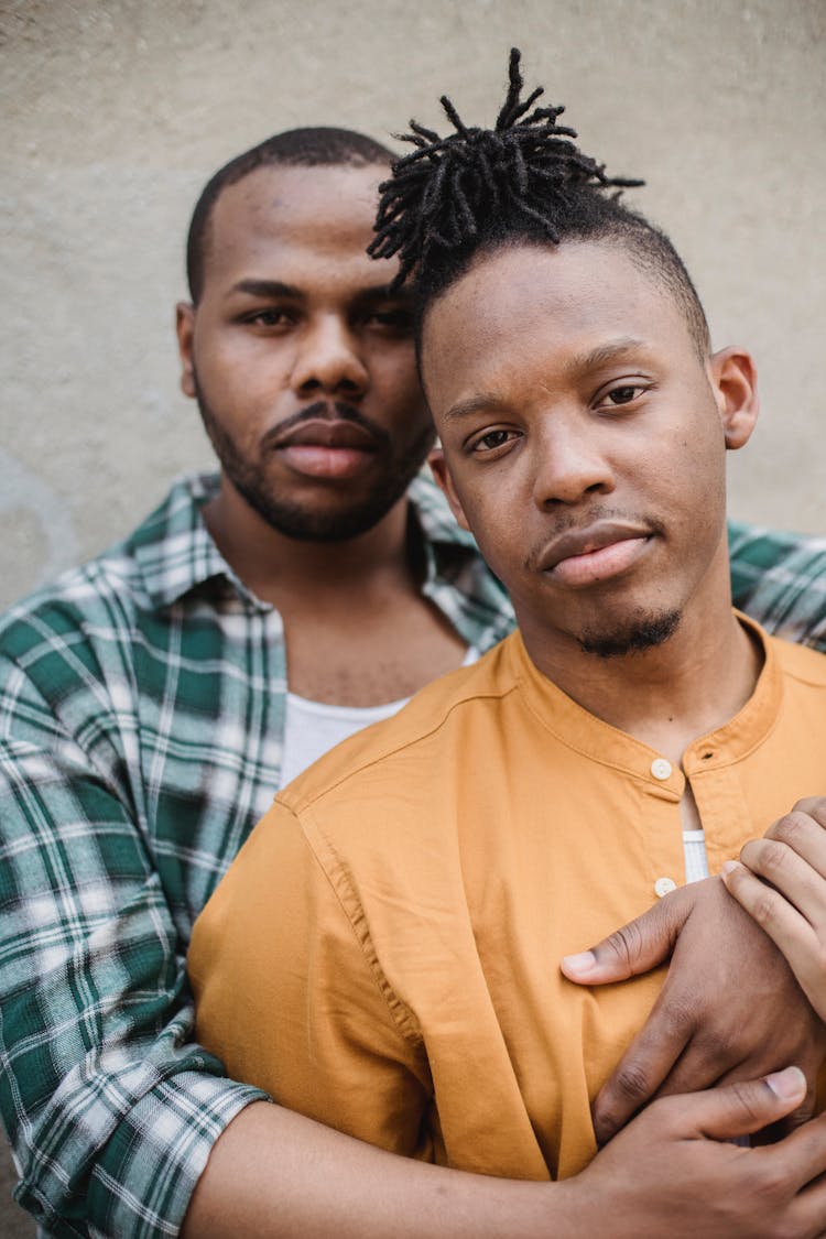 Man Standing Behind Other Man And Embracing Him With Arms