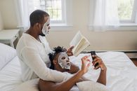 A Couple Doing their Own Stuffs while Staying on Bed