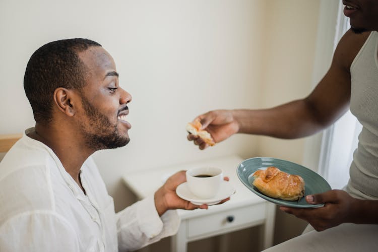 A Person Handing A Croissant To The Man