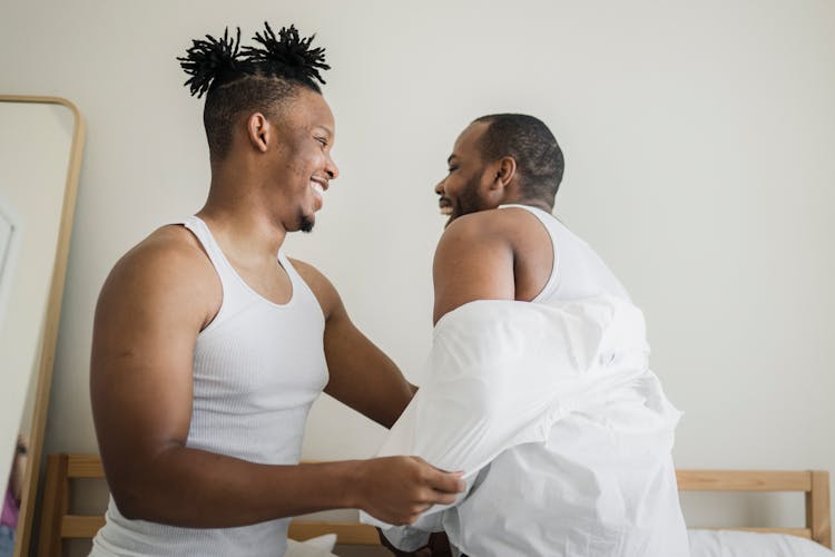 Man Taking Off Shirt From Other Man In Bedroom