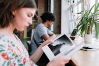 在光线自然、绿植环绕的舒适咖啡馆里，两名年轻人正享受着一节轻松的阅读课