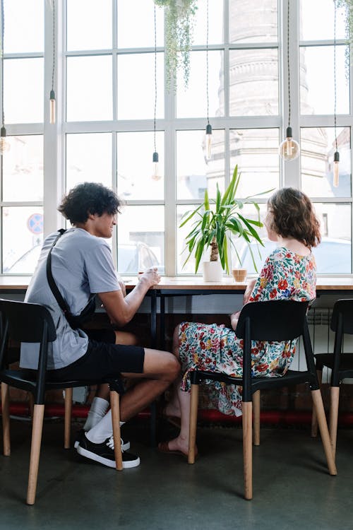 Free Man in White Shirt Sitting on Chair Beside Girl in Pink Shirt Stock Photo