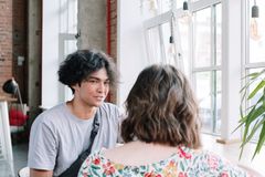 A young couple enjoying a conversation by the window in a modern, airy cafe.