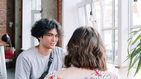A young couple enjoying a conversation by the window in a modern, airy cafe.