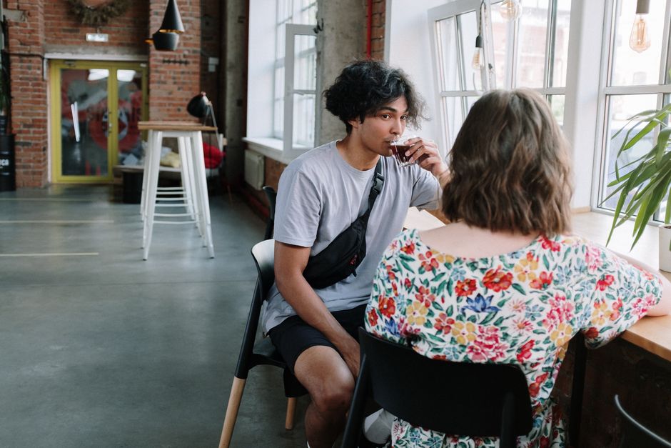 Deux personnes en conversation détendue autour d'un café, échangeant sur un projet