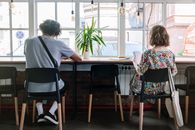 Woman in Black Pink and Green Floral Dress Sitting on Chair