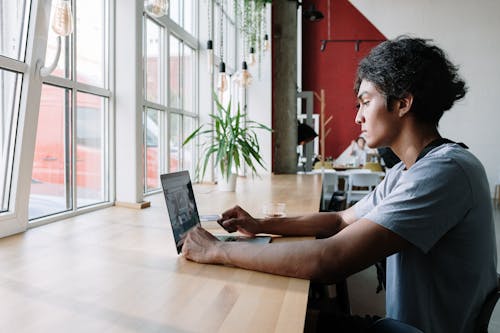 Man In Witte Ronde Hals T Shirt Met Laptopcomputer Op Bruin Houten Tafel