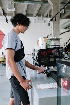 A young man makes a contactless payment with his smartphone at a stylish coffee shop.
