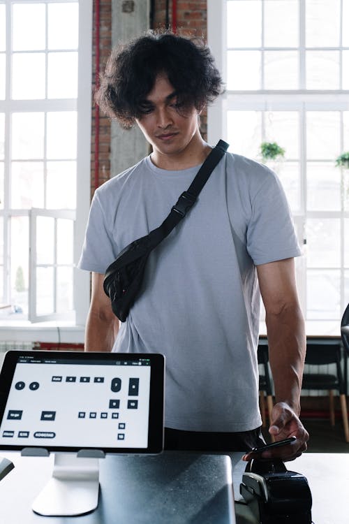 Man in White Crew Neck T-shirt Standing Near Black Laptop Computer