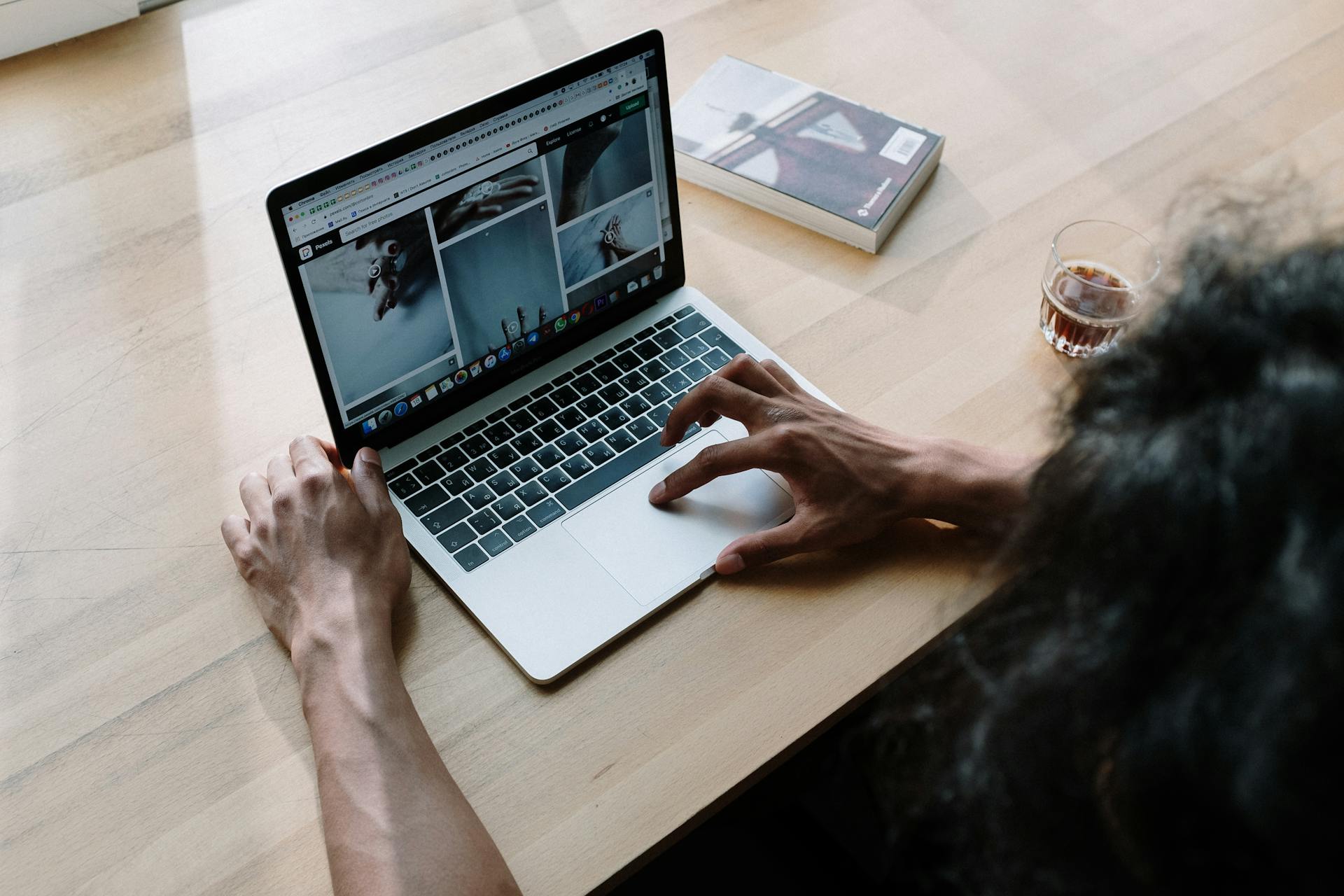 Person Using Macbook Pro on Brown Wooden Table