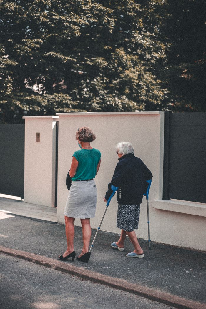 Oudere vrouw wandelt buiten samen met een begeleider