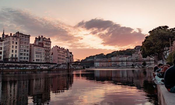Beautiful sunset view over the Saone River in Lyon, France, showcasing urban townhouses and reflections.