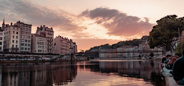 Beautiful sunset view over the Saone River in Lyon, France, showcasing urban townhouses and reflections.
