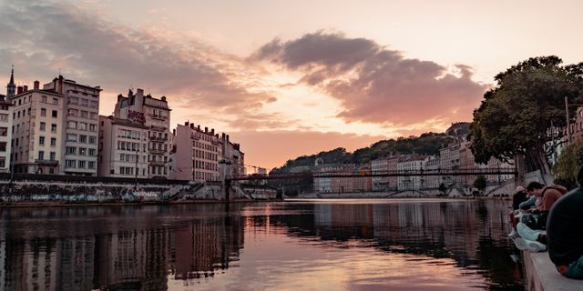 Beautiful sunset view over the Saone River in Lyon, France, showcasing urban townhouses and reflections.