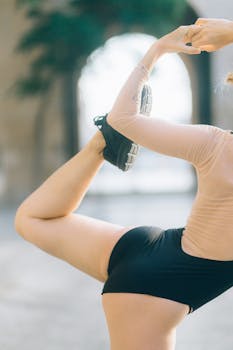 A flexible woman performing a yoga pose outdoors showcasing balance and fitness.