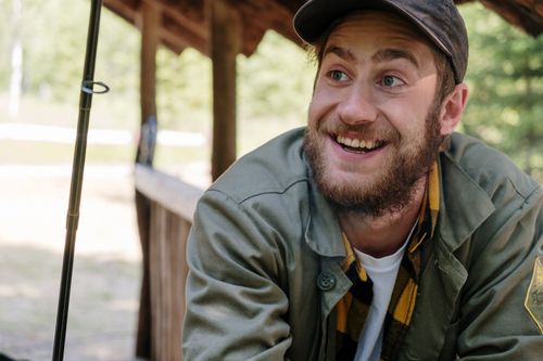 Free Happy fisherman enjoying a relaxing day outdoors with his fishing gear, exuding joy in the countryside. Stock Photo