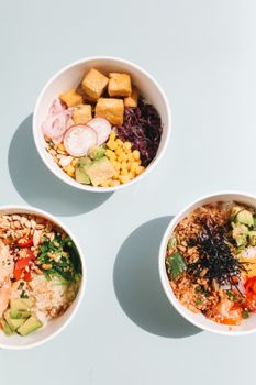 三个五颜六色的戳碗，配有鳄梨、玉米和豆腐等新鲜食材