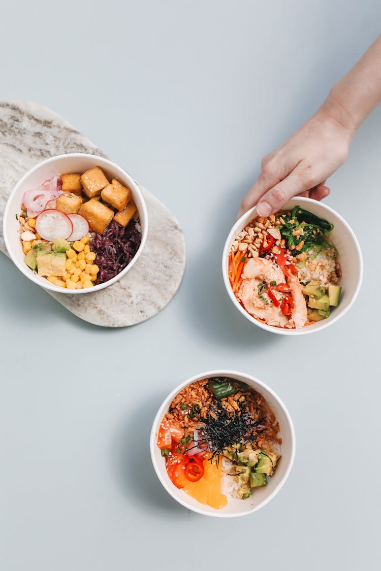 Overhead Shot Of A Person's Hand Holding A Poke Bowl