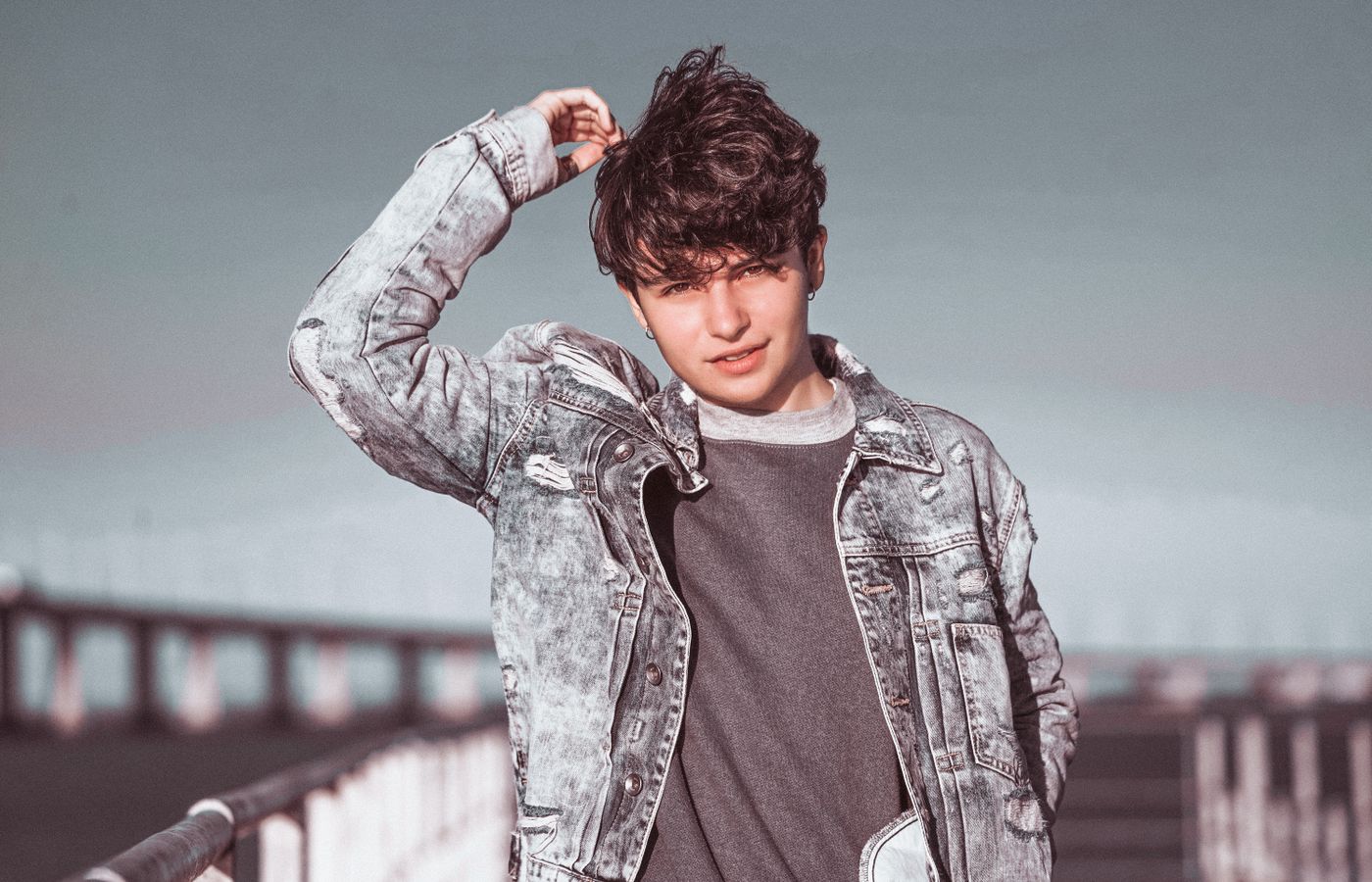 Teenager wearing a denim jacket outside on a bridge. Perfect for lifestyle themes.