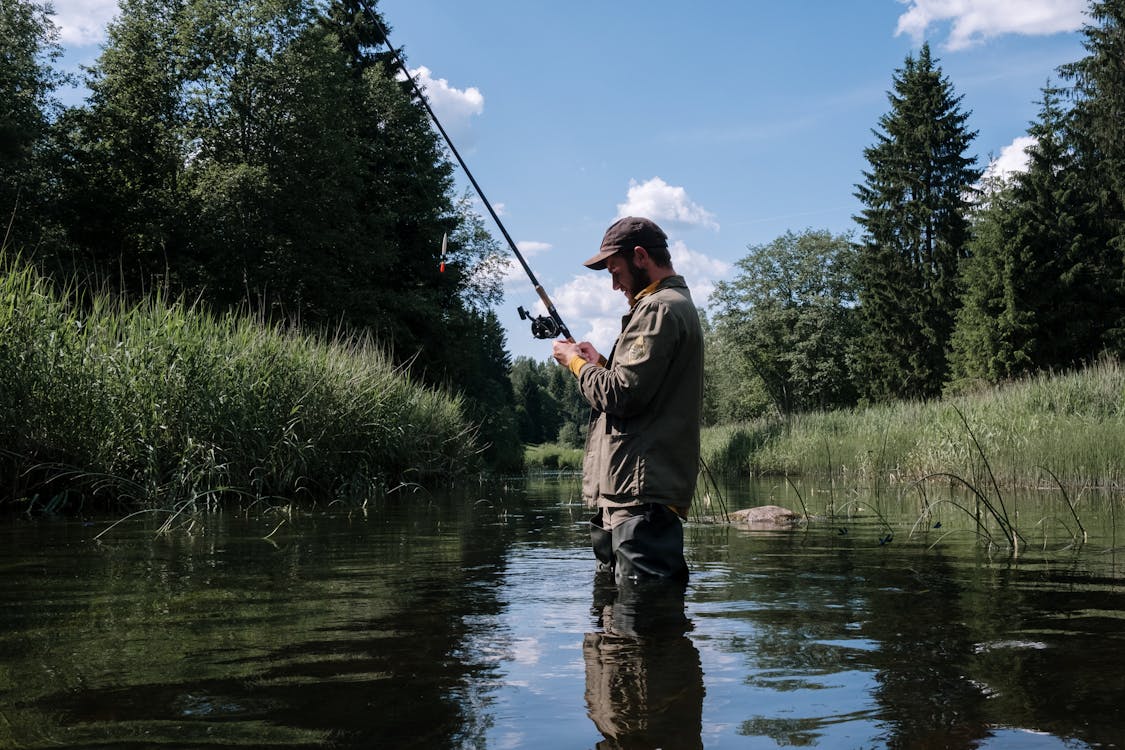 Man in Green Jacket Fishing on River