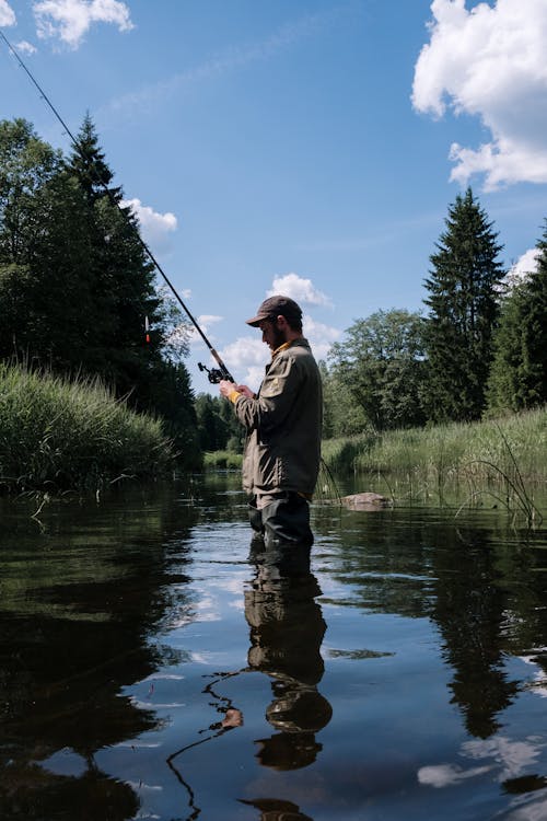 Man in Gray Jacket Fishing on River