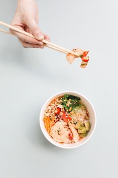A delicious poke bowl featuring shrimp, avocado, veggies, and grains, captured with a top-down view.