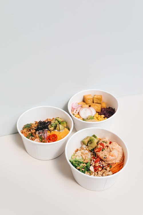 Free Three delicious healthy poke bowls with fresh ingredients on a white surface, perfect for food photography. Stock Photo