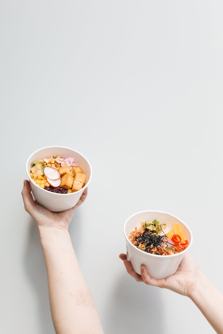 Hands Holding Poke Bowls 