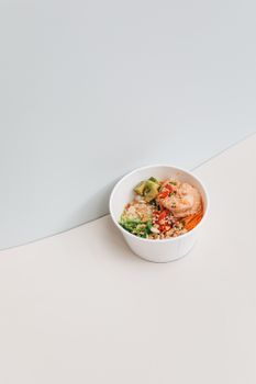 Minimalist photo of a poke bowl with shrimp, avocado, and colorful veggies in a white bowl.