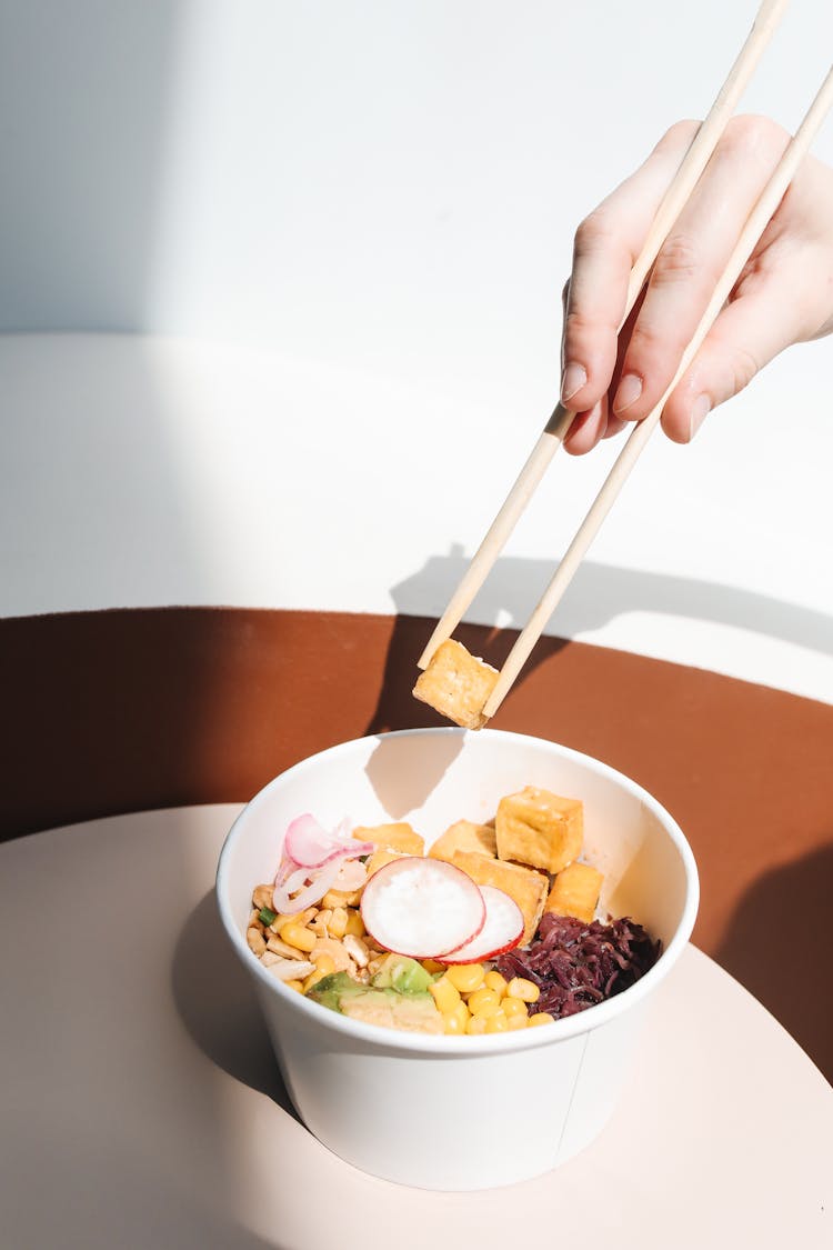 Photo Of A Person's Hand Getting Tofu From A Poke Bowl