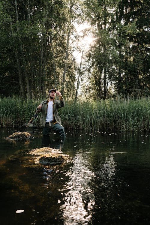 Man in Blue Shirt and Black Pants Fishing on River · Free Stock Photo