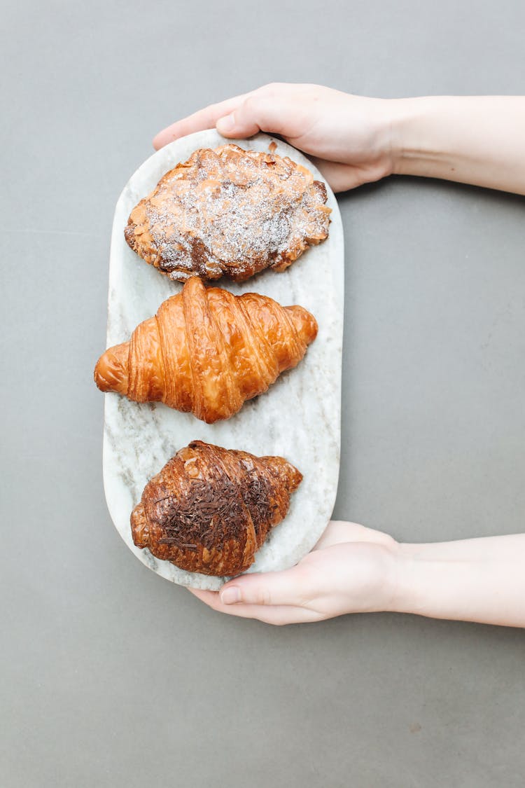 Overhead Shot Of A Person Holding A Board With Croissants