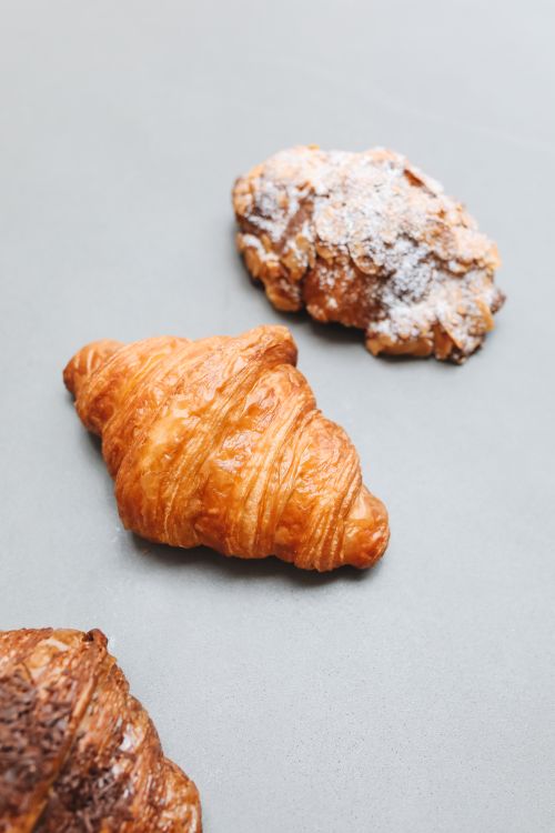 Free Three varieties of croissants, including almond and plain, on a grey surface. Stock Photo