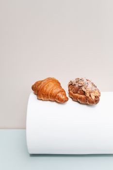 Two freshly baked croissants elegantly displayed on a minimalist background. Perfect for food photography enthusiasts.