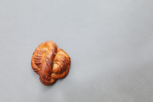 Simple overhead view of a freshly baked cardamom knot on a gray background, perfect for food and bakery themes.