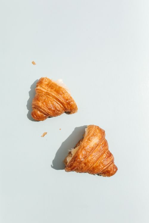 Free Top view of fresh croissant halves on a minimalist pastel background, perfect for bakery themes. Stock Photo