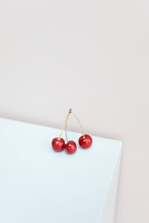 A Few Red Cherries on the Edge of a White Table