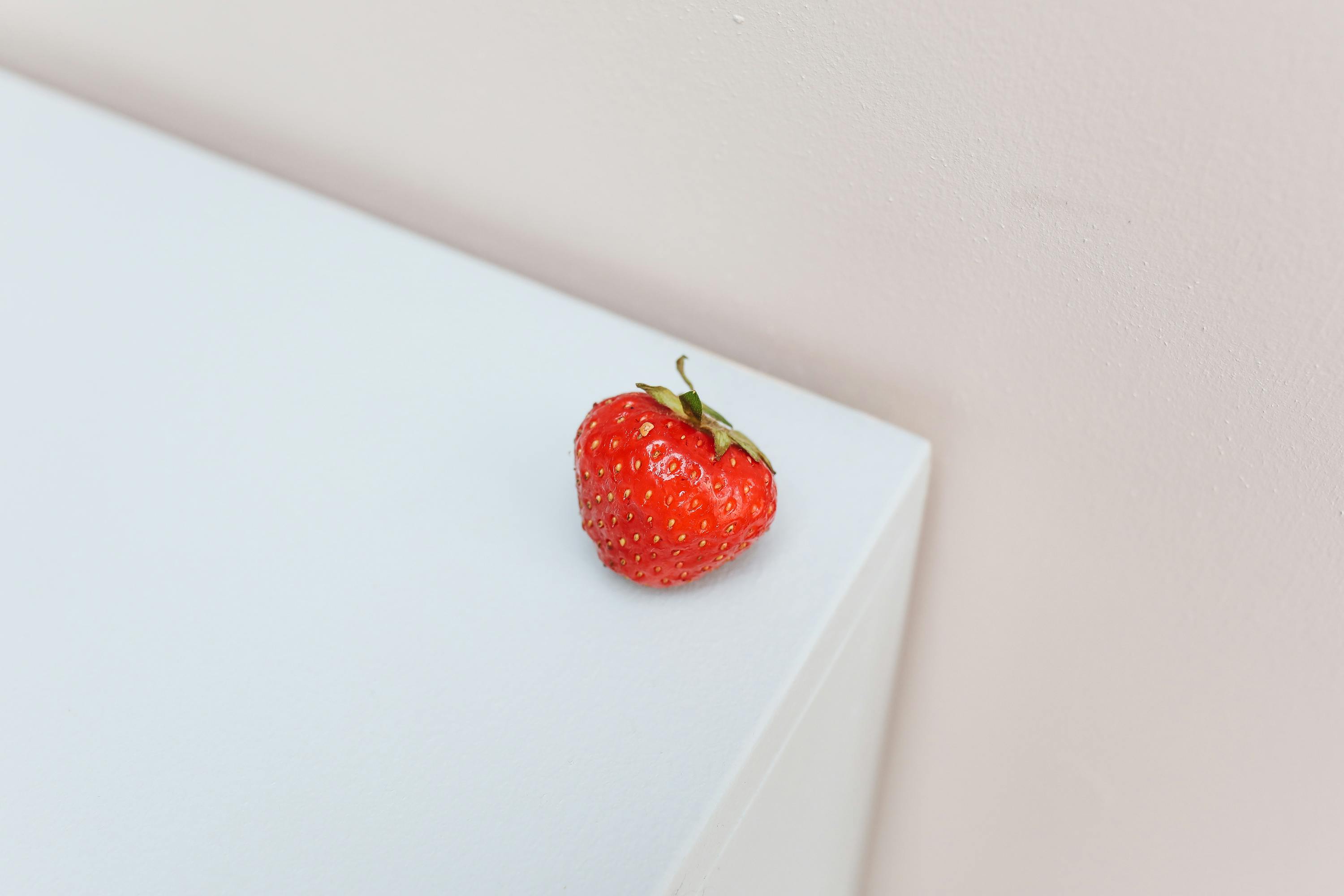 a piece of red strawberry on the edge of a surface