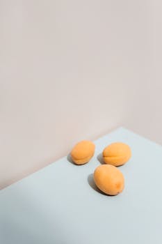 Three apricots on a light blue surface with ample copy space, perfect for minimalistic designs.