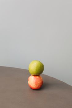 A minimalist photo of a green and red apple stacked on a neutral surface, offering ample copy space.