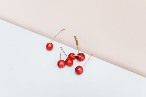 Free A minimalist photo of fresh red cherries on a soft pastel surface, showcasing natural elegance. Stock Photo