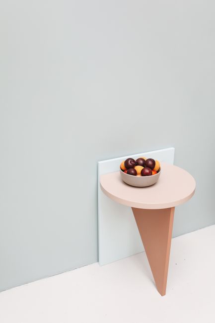 A modern still life with a bowl of apricots and plums on a minimalist table.