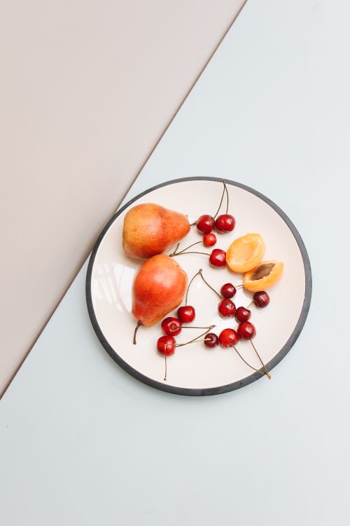 Free A vibrant display of pears, cherries, and apricot on a ceramic plate. Perfect for food photography. Stock Photo